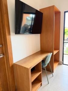 a room with a desk and a tv on a wall at PF Hotel in San Felipe de Puerto Plata