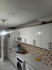 a kitchen with white cabinets and a washing machine at Alyakek Apartment in Istanbul