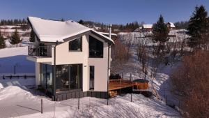 a white house in the snow with a deck at Dzvin in Slavske