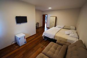 a bedroom with a bed and a couch and a flat screen tv at Hotel Pedra Moura in Vacaria