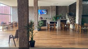 a dining room with tables and chairs and a fireplace at Hotel Pedra Moura in Vacaria