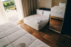 a bedroom with two beds and a window with a view at Roga Village in Atibaia