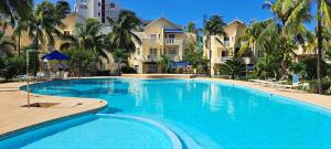 a large swimming pool with palm trees and houses at Cool Studio in Flic-en-Flac