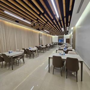 a dining room with white tables and chairs at BAZ Hotel Airport Road in Baghdād