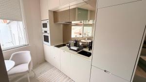 a kitchen with white cabinets and a white chair at Spacious studio apartment in the heart of Cascais historic center in Cascais