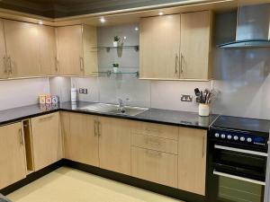 a kitchen with wooden cabinets and a sink at Kirkwall town centre apartment 3 in Kirkwall +29 photos