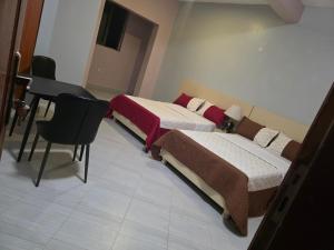 a room with two beds and a desk and a piano at Vegas Chillout Suites in Kampala