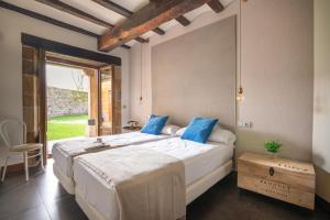 a bedroom with a large white bed with blue pillows at Jardín Botánico in Lloreda