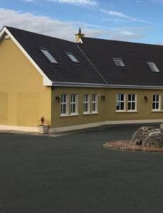 a large yellow house with a black roof at Curraghchase Cottage in Limerick