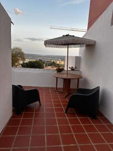 a patio with a table and chairs and an umbrella at Casa do Alto da Torre in Abrantes