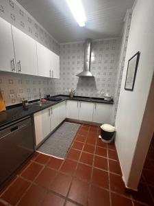 a kitchen with white cabinets and a red tile floor at Casa do Alto da Torre in Abrantes