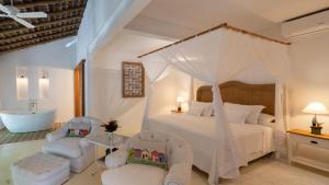 a bedroom with a bed and two chairs and a tub at Pousada Tangará in Trancoso +47 photos