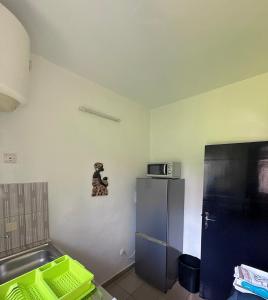 a small kitchen with a refrigerator and a microwave at Residence Mamie Léo in Abidjan