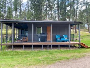a small house with blue chairs on the porch at Cabin 1 at Horse Creek Resort in Rapid City