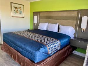 a bed in a hotel room with a blue comforter at Executive Inn & Suites in Beaumont