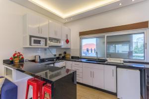 a kitchen with white cabinets and a large window at City Rental London theme in Batroûn +12 photos