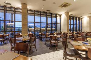 a restaurant with tables and chairs and large windows at Cullinan Hplus Premium in Brasília