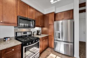 a kitchen with wooden cabinets and stainless steel appliances at Poolside Greens 2BR Legacy Villa in La Quinta