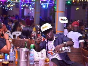 a man sitting at a table with a bottle of water at Vegas Chillout Suites in Kampala