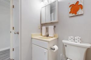 a white bathroom with a toilet and a sink at NTBTR329 Totally Topsail in North Topsail Beach +26 photos