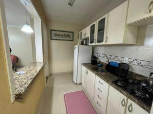a kitchen with a white refrigerator and white cabinets at AP perto do HSVP com estacionamento in Passo Fundo