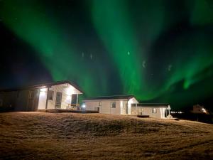 a house under the northern lights in the sky at Farmer's Guest House in Hella
