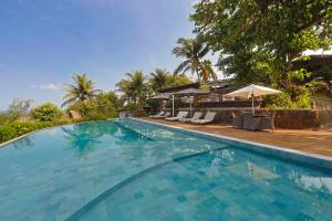 a large swimming pool with chairs and an umbrella at Pousada Zé Maria in Fernando de Noronha