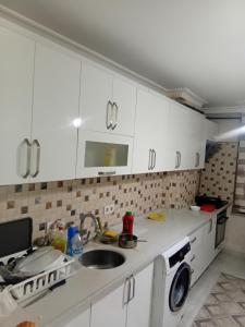 a kitchen with white cabinets and a sink and a washing machine at Edebiyat Apartments in Istanbul