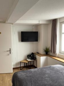 a bedroom with a bed and a flat screen tv on the wall at Hotel Central - Self Check-in in Luchsingen