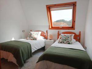 two beds in a room with a window at Mar de Laxe Vistas al mar y Costa da Morte in Cabana de Bergantiños