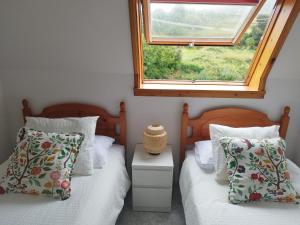 two twin beds in a bedroom with a window at Mar de Laxe Vistas al mar y Costa da Morte in Cabana de Bergantiños