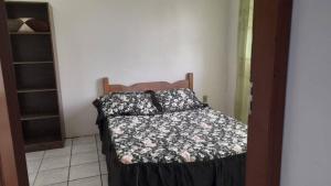 a bedroom with a bed with a black and white comforter at Casa Amarela in Imbituba