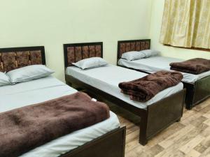 a room with three beds with brown blankets at Tridev Hills in Ujjain