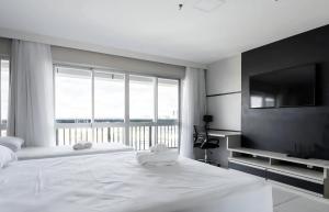 a bedroom with a large white bed and a large window at Flat com vista espetacular no centro de Brasília Vision Work and live in Brasília