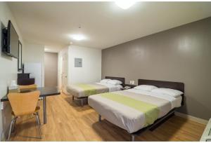 a room with two beds and a desk and a table at Studio 6 Extended Stay - Augusta, GA - Fort Gordon in Augusta