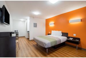 a bedroom with a bed with an orange wall at Studio 6 Extended Stay - Augusta, GA - Fort Gordon in Augusta