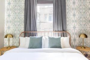 a bed with blue and white pillows and a window at Inn at Gough in San Francisco