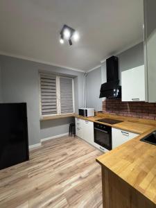 a kitchen with white cabinets and a wooden floor at Apartament Centrum in Płock