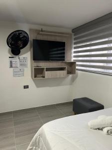 a bedroom with a bed and a flat screen tv on the wall at Casa Vernazza in Manizales