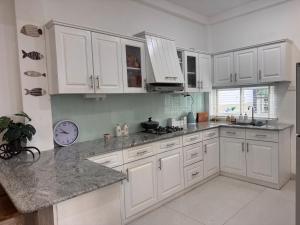 a kitchen with white cabinets and a clock on the wall at Villa Auxesiaa in Wattala