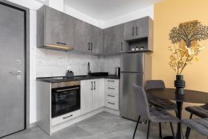 a kitchen with a table and a stainless steel refrigerator at Anatoli Urban Apartment with private parking in Xanthi