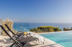 a pair of chairs and a table next to a swimming pool at Villa Anatoli in Achlia