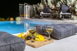 two glasses of wine on a tray next to a swimming pool at Villa Anatoli in Achlia