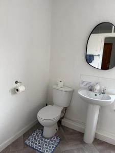 a white bathroom with a toilet and a sink at 17 Main Street in St Bees +4 photos
