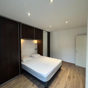 a bedroom with a bed with white sheets and wooden floors at Le Nid Bressan in Bourg-en-Bresse