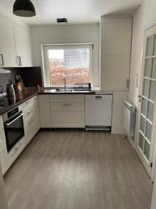 eine Küche mit weißen Schränken, einer Spüle und einem Fenster in der Unterkunft Rødt hus in Givskud