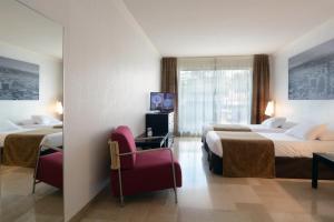 a hotel room with two beds and a chair at Aparthotel Adagio Nice Promenade des Anglais in Nice