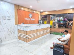 a man sitting in front of a vista sound store at Hotel Visara Grand in Gokarna
