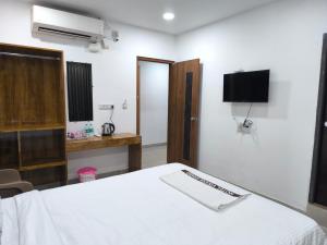 a bedroom with a white bed and a tv on the wall at Hotel Visara Grand in Gokarna
