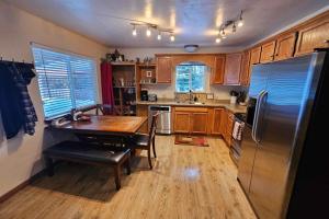 a kitchen with a table and a stainless steel refrigerator at Home w/ Hot Tub, 3 Mi to Lake & Ponderosa Park in McCall